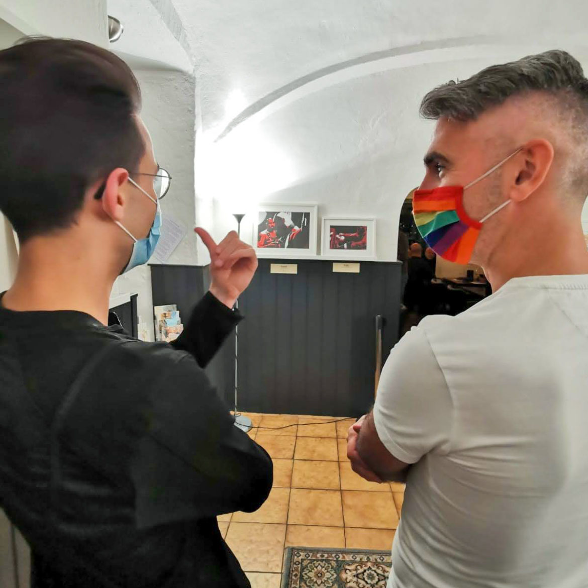 Der Künstler Lars van Roosendaal (rechts) im Gespräch mit einem Besucher vor gerahmten Porträts bei der Vernissage der Ausstellung PRIDE, SHAME & PREJUDICE im R.O.P.P., Wien, Oktober 2020